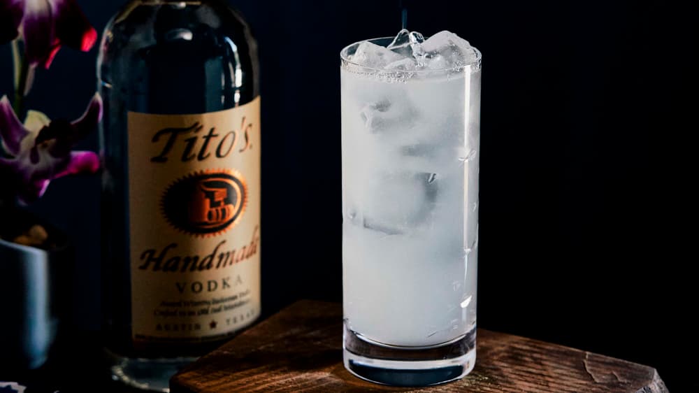 Tito's Yuzu Collins in a tall glass with a bottle of Tito's Vodka