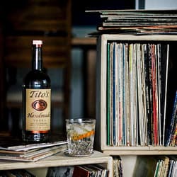 Bottle of Tito's Vodka and a cocktail in a room of vinyl records