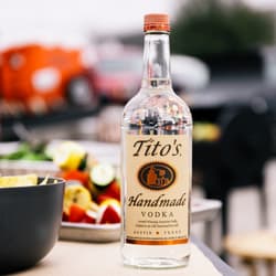 Bottle of Tito's Handmade Vodka on a table with snacks at a tailgate