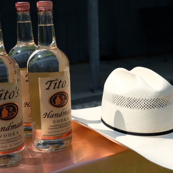 Tito's Handmade Vodka bottles sitting on a bar with a cowboy hat.