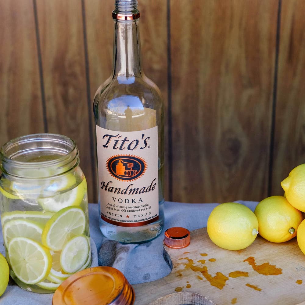 Tito's Handmade Vodka bottle and a mason jar full of tito's and lemons