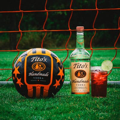 Tito's Vodka bottle and cocktail with a Tito's Soccer Ball