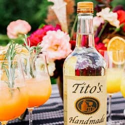 Dining table with spring flowers, cocktails, and a Tito's Handmade Vodka bottle