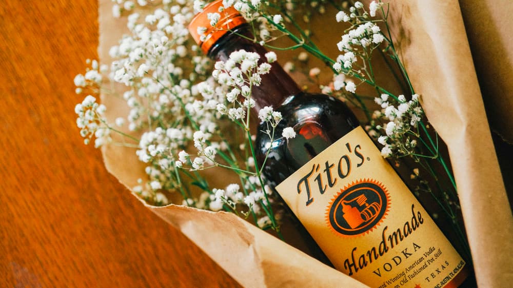Tito's Vodka bottle with hibiscus petals inside