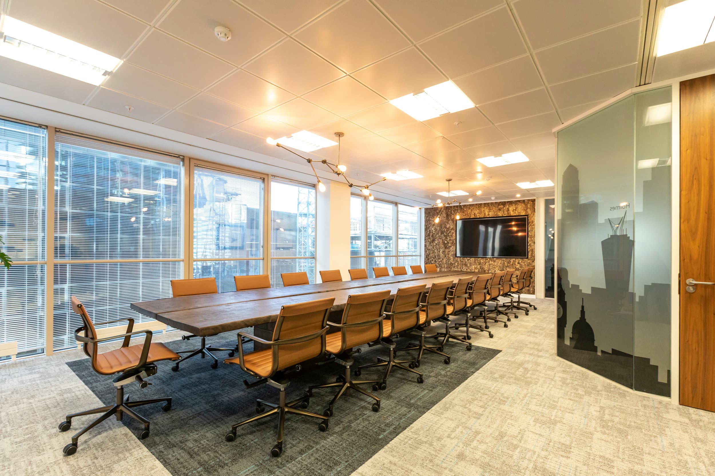 Long boardroom table with caramel leather chairs, bark wall and manifestation