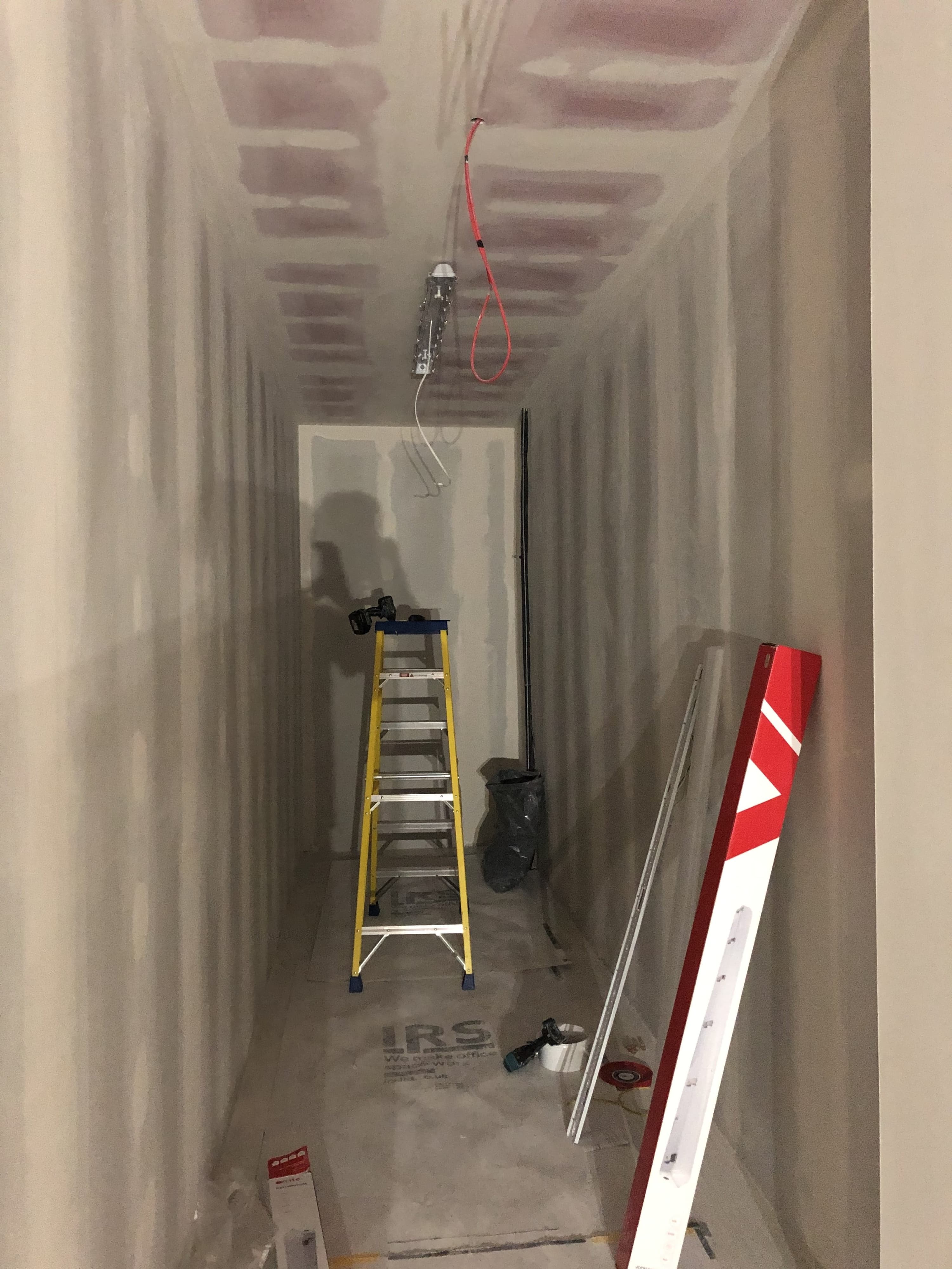 Tape and jointed plasterboard walls with ladder in background