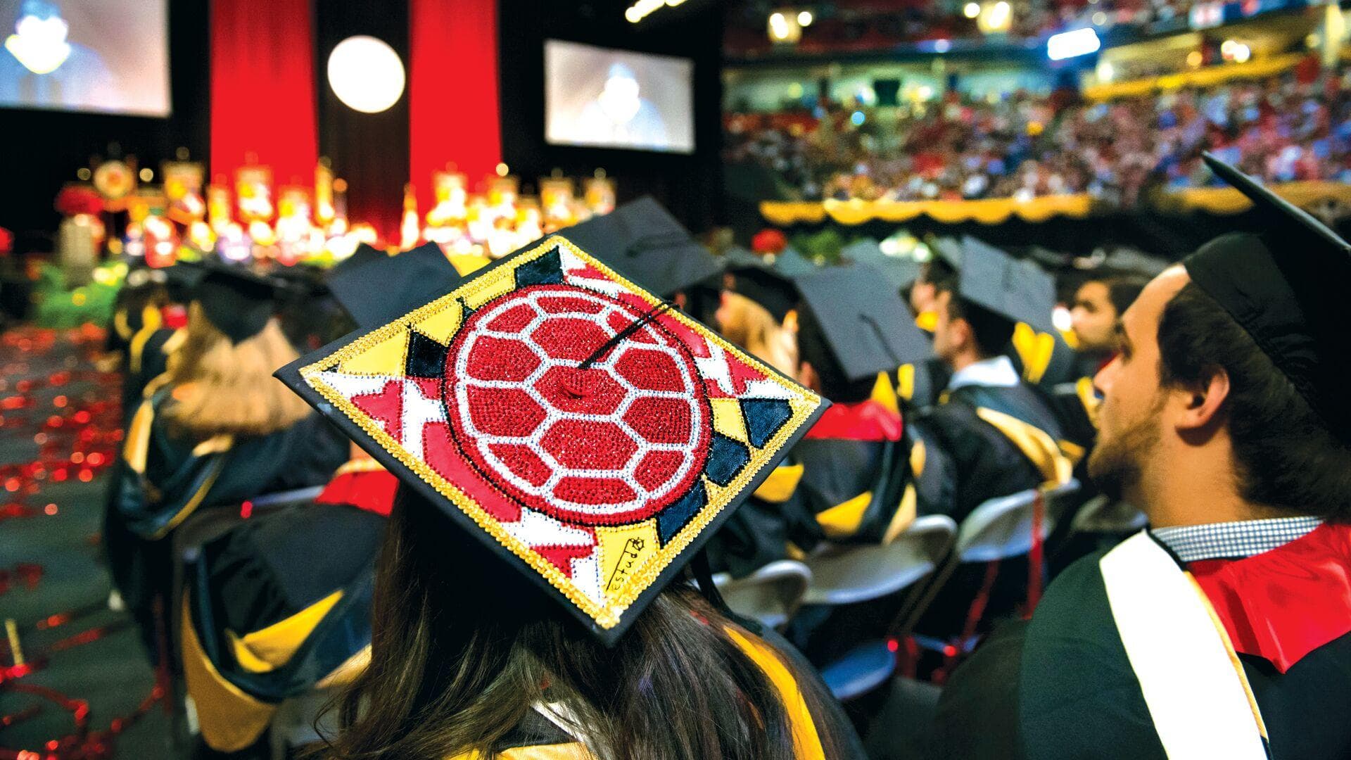University of Maryland's Commencement, focused on a graduation cap bedazzled in the Maryland colors of Black Gold, Red and White depicting the Red Shell logo of Testudo