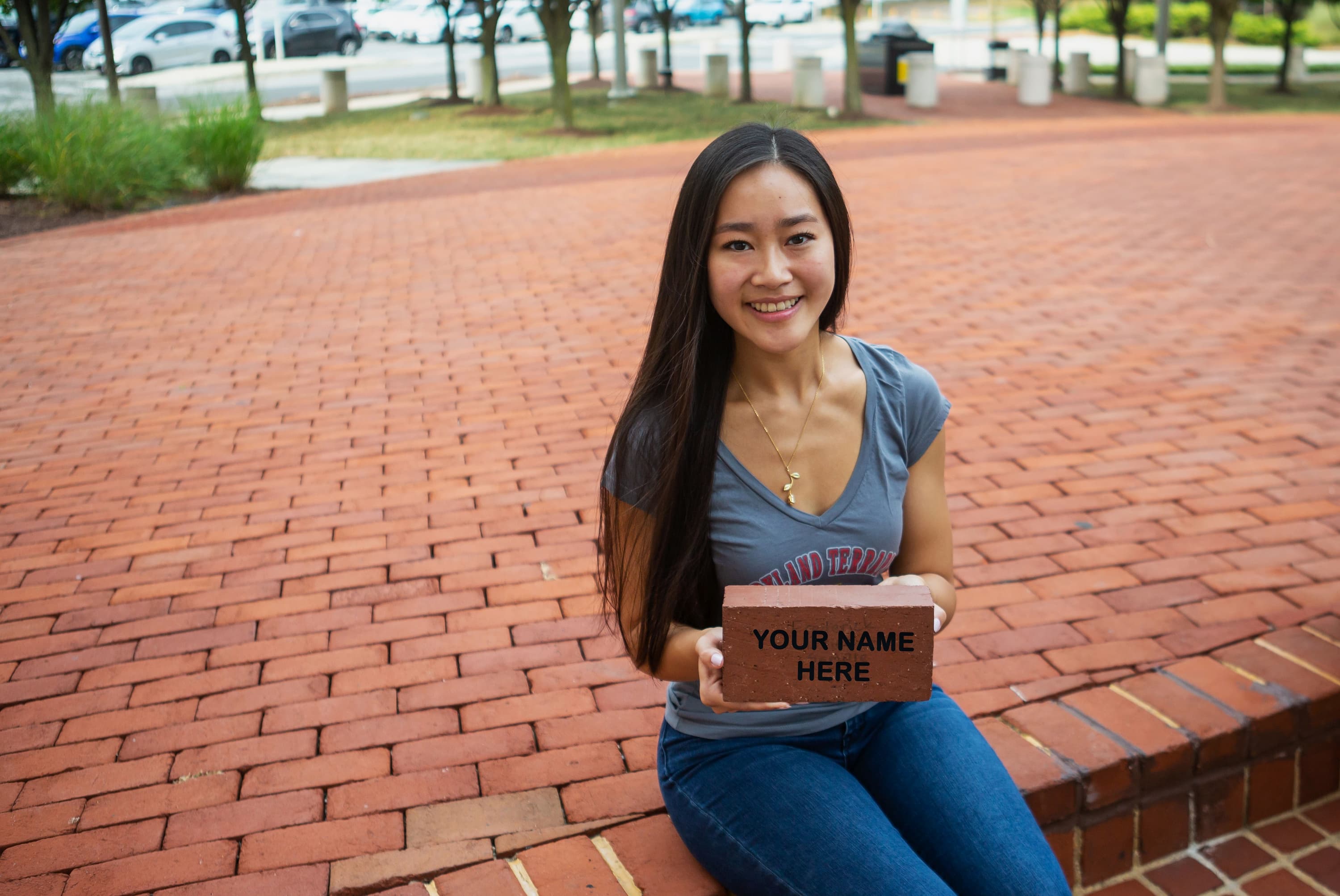 Emily Leo '22 holding a personalized brick on Legacy Plaza.