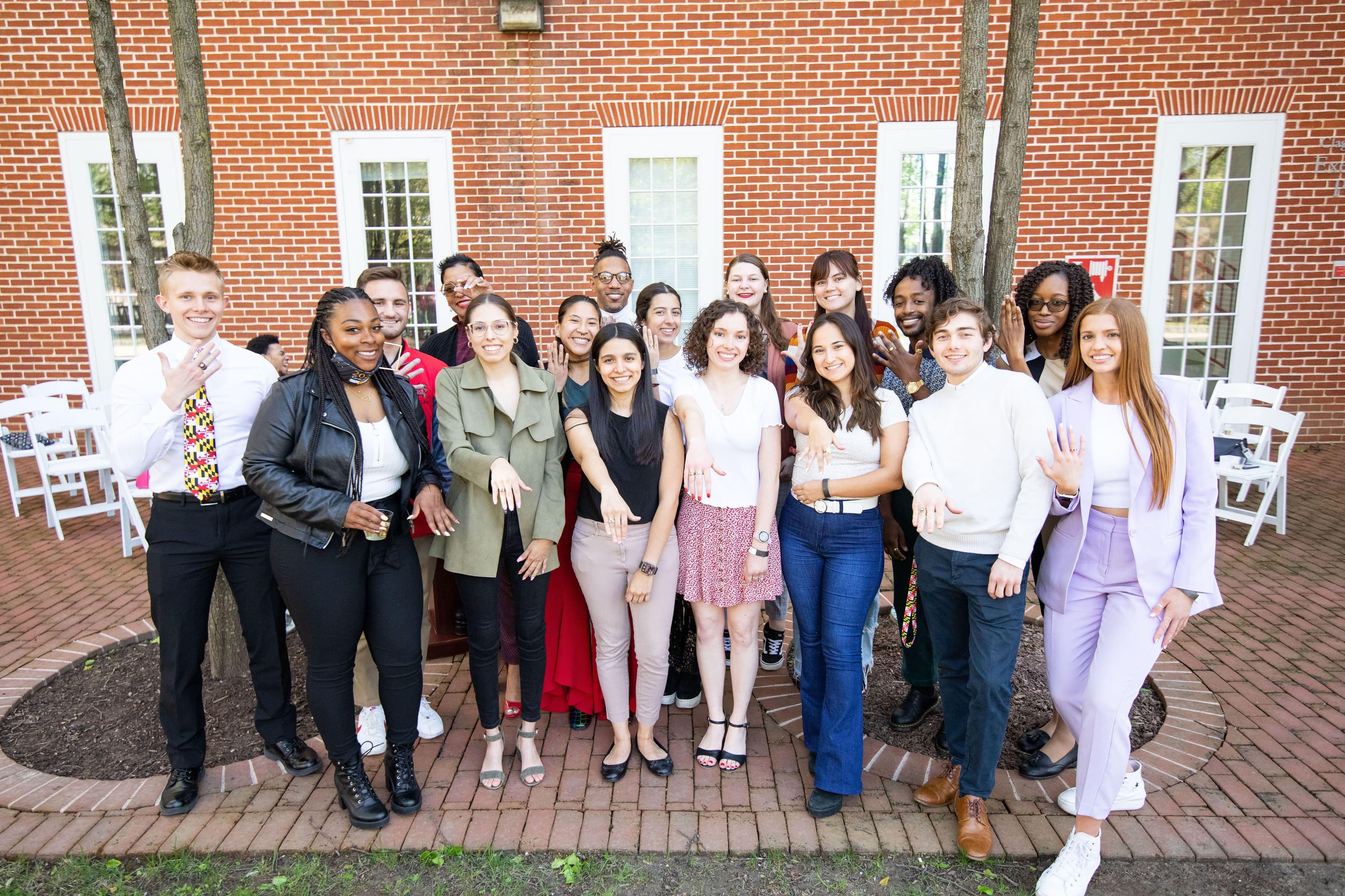 A group of University of Maryland alumni pose outside with their class rings.