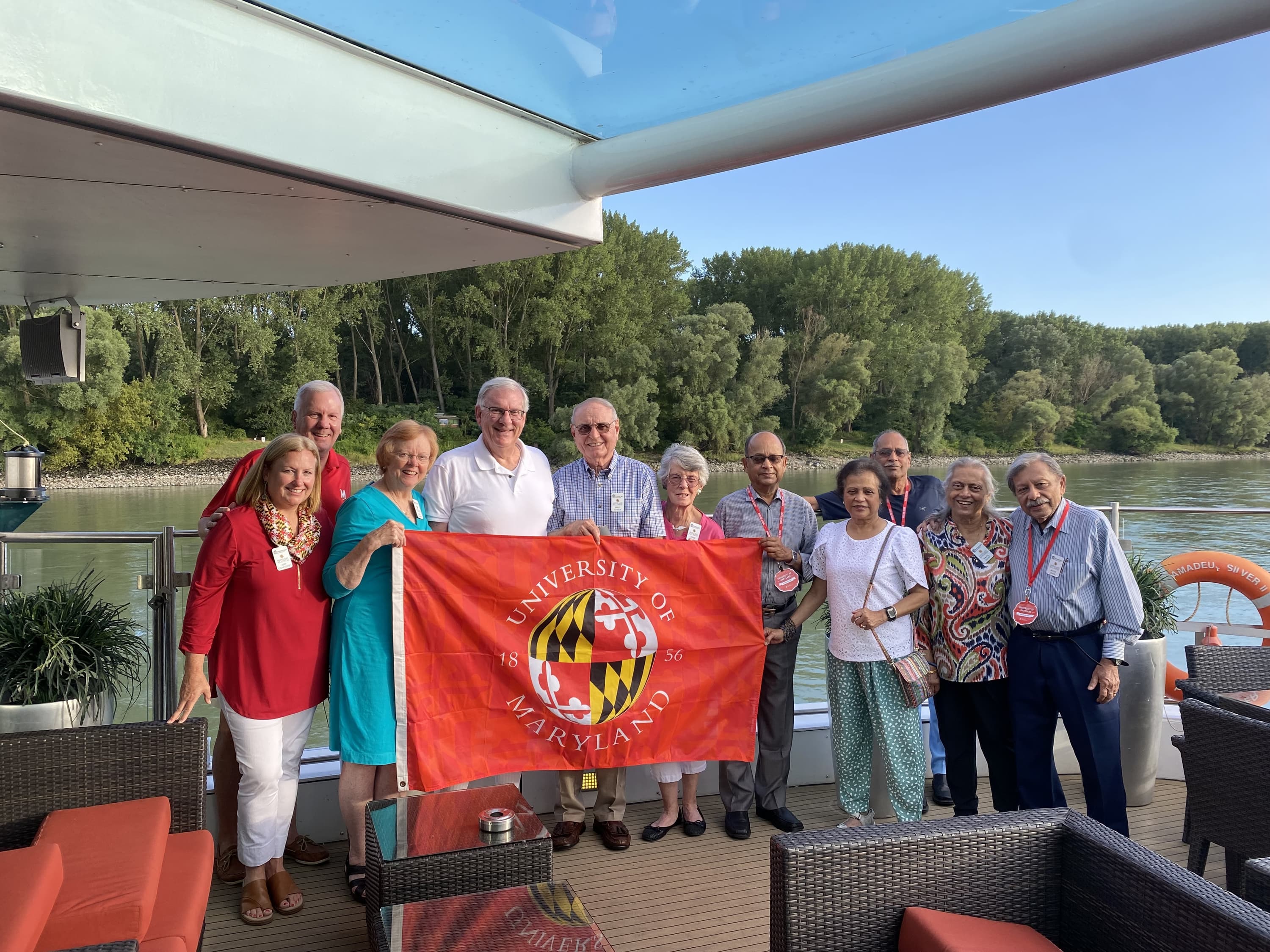 A group of Terp alums hold up a University of Maryland flag on a previous trip.