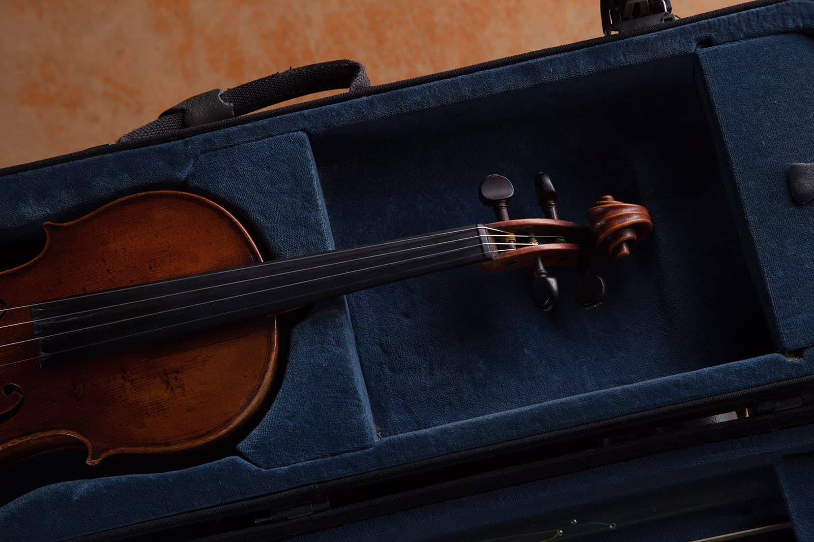 A violin rests inside an opened blue violin case.