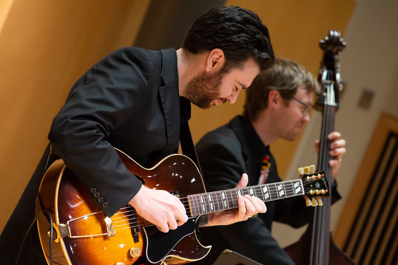 Students play electric guitars on stage.