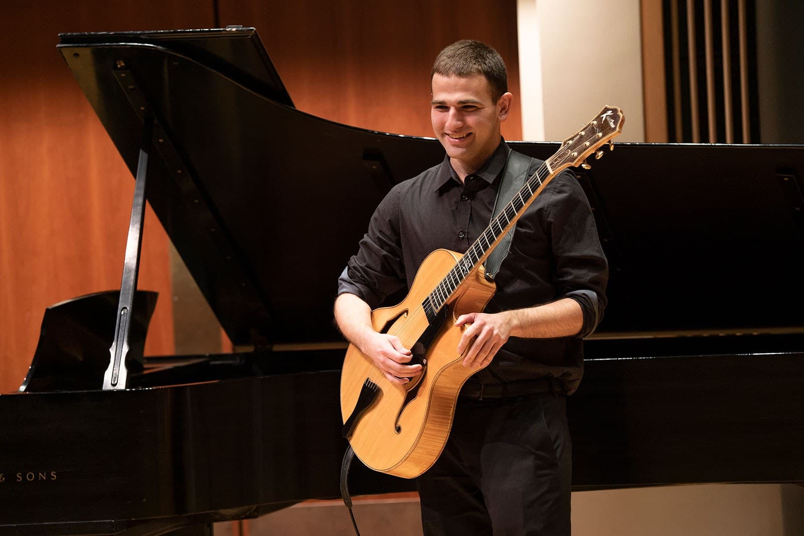 Student plays guitar on stage.