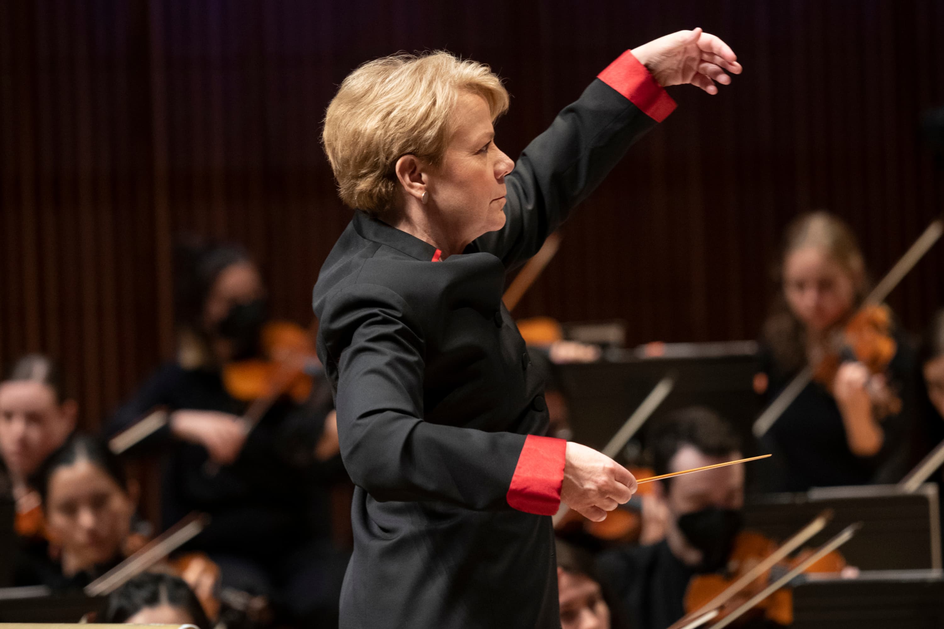 Marin Alsop conducts an orchestra on stage.