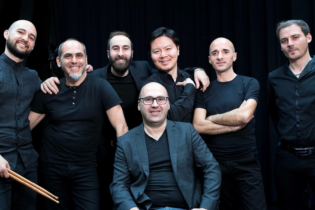 Seven men wearing black outfits pose for a picture.