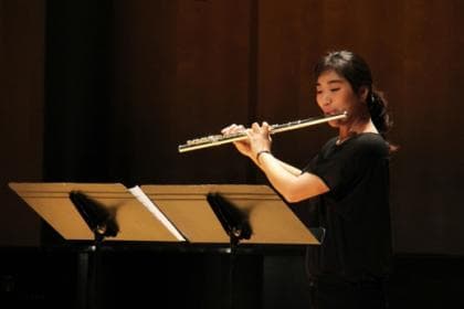 Student plays flute on stage.