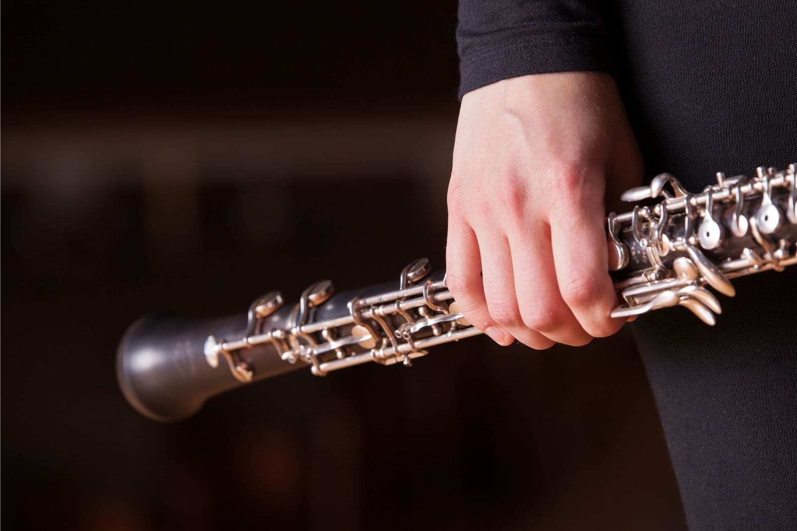 A hand holds an oboe.