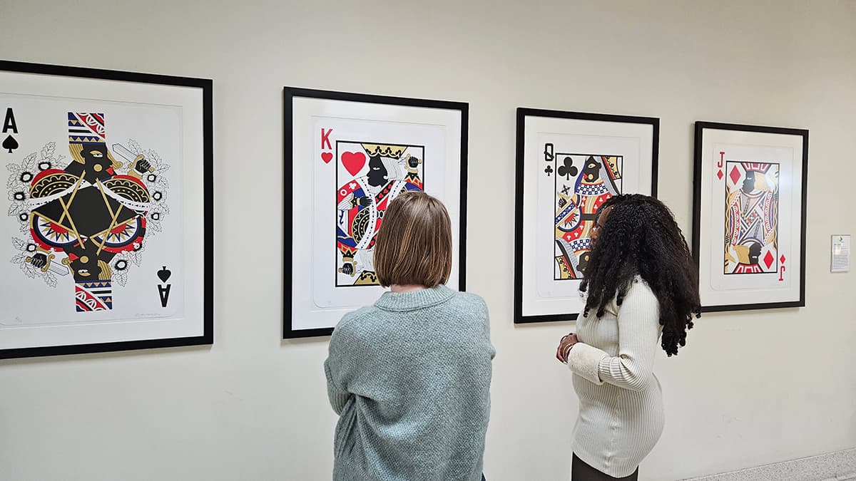Two students looking at Derrick Adam's "Game Changing" print series