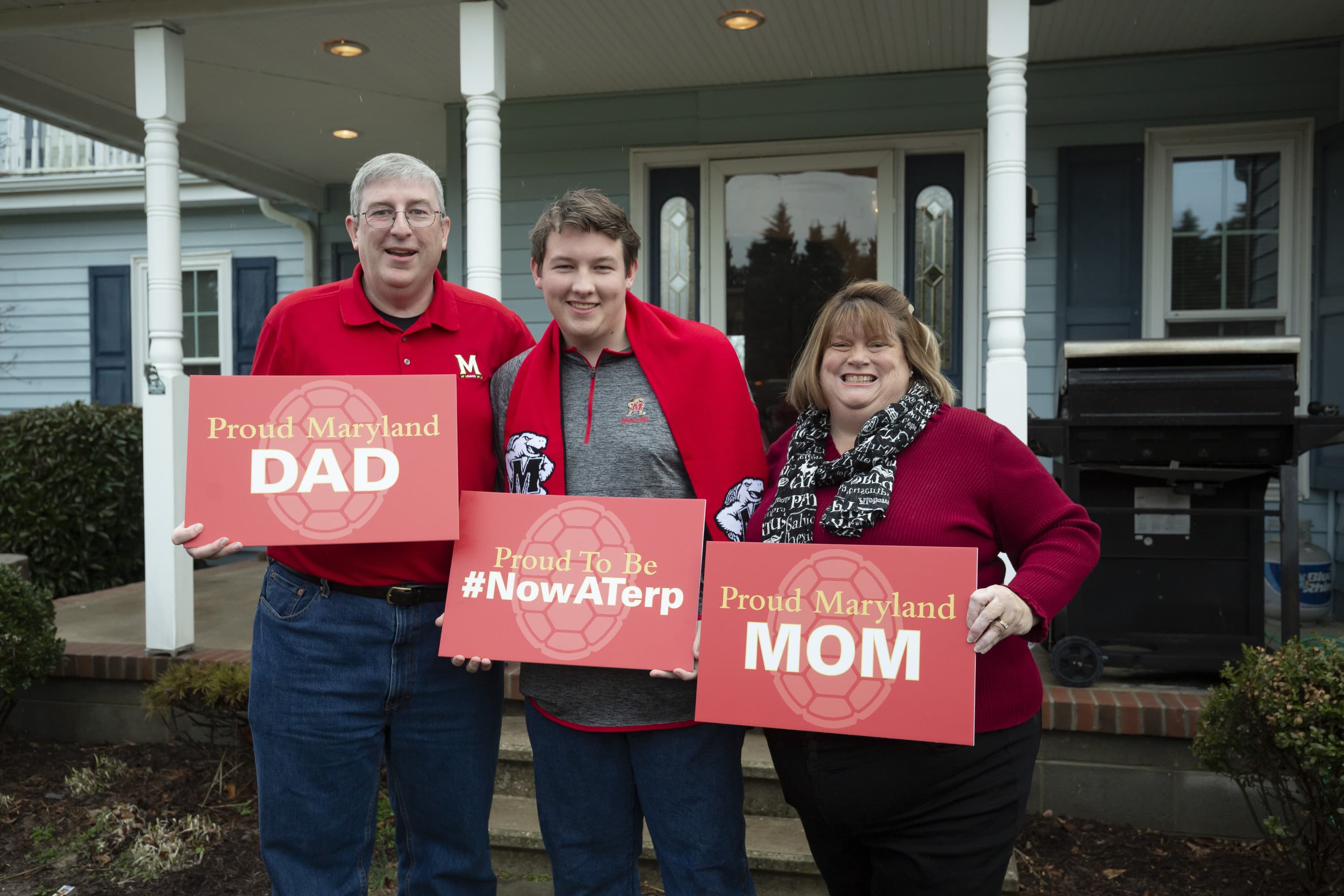 Father, mother and son pose for camera holding signs