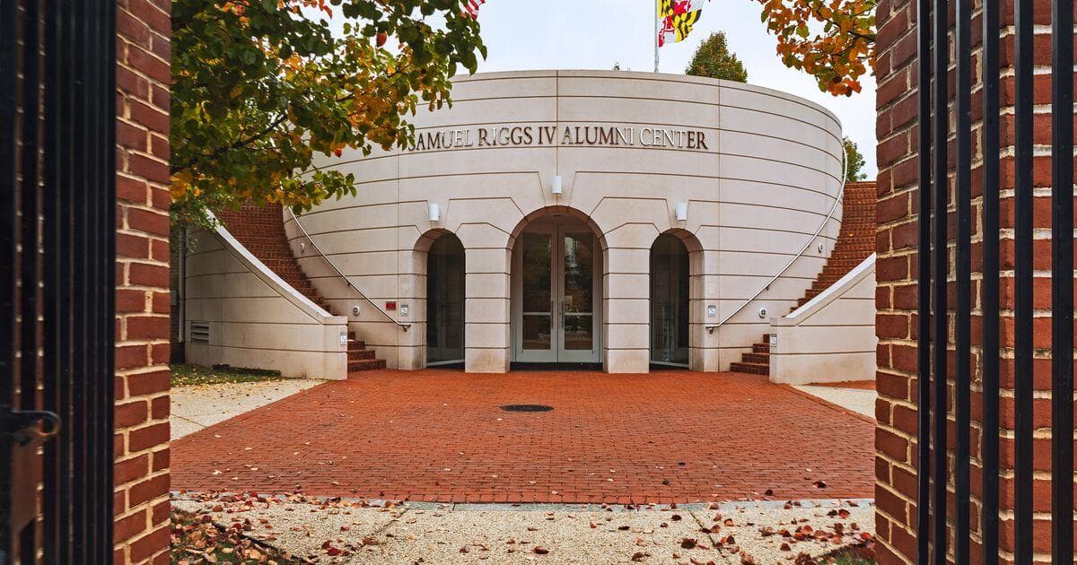 Exterior view of Riggs Alumni Center with fall foliage as seen through the gates of Moxley Gardens.