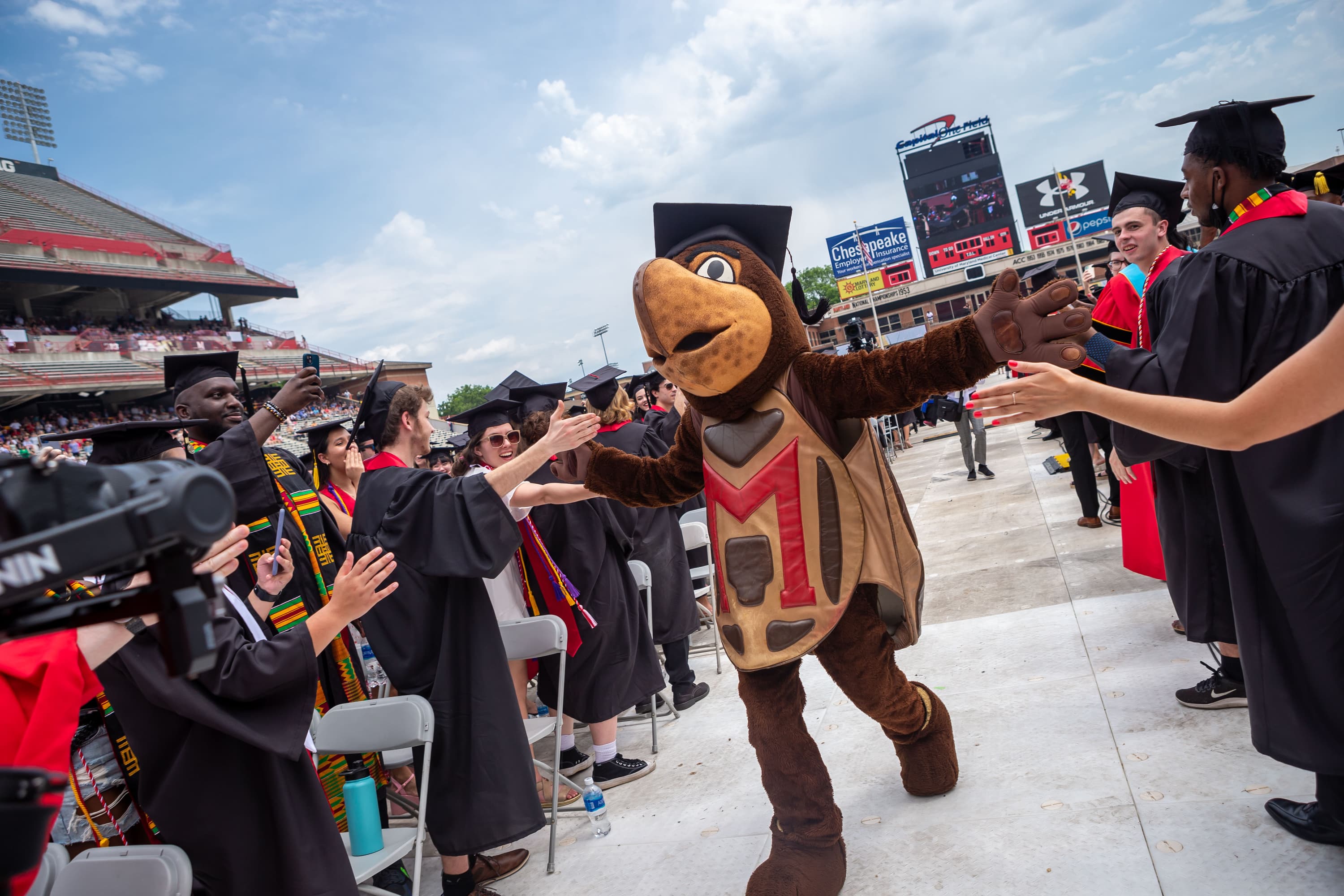 Testudo high-fiving students at commencement