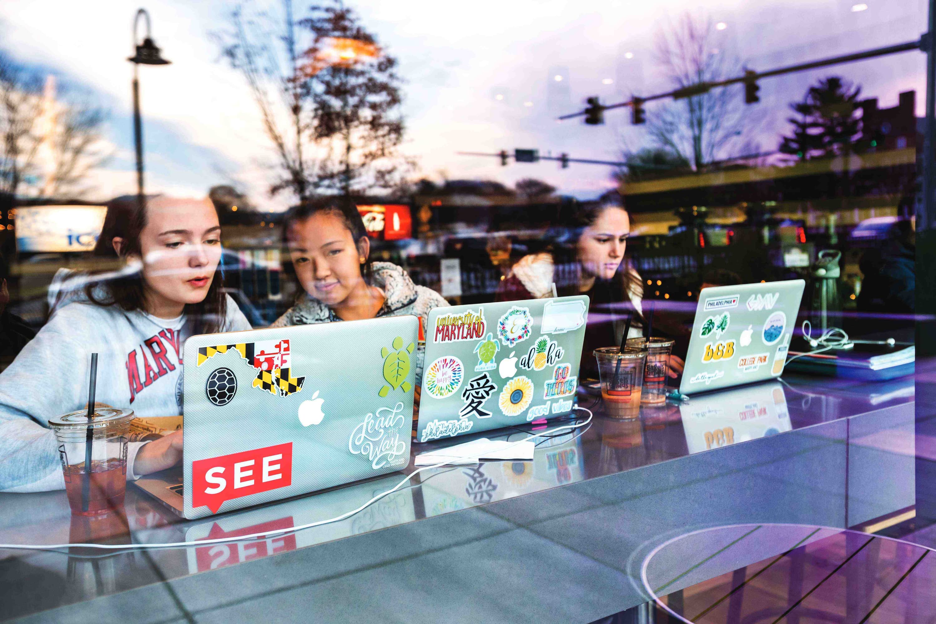 Three female students on their laptops in coffee shop