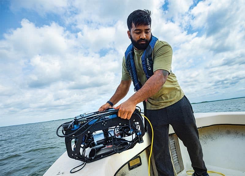 Keshav Rajasekaran ﻿Ph.D. ’22 ﻿prepares to launch an ﻿underwater robot to ﻿seek oysters.