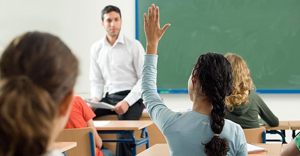 student raises hand in classroom