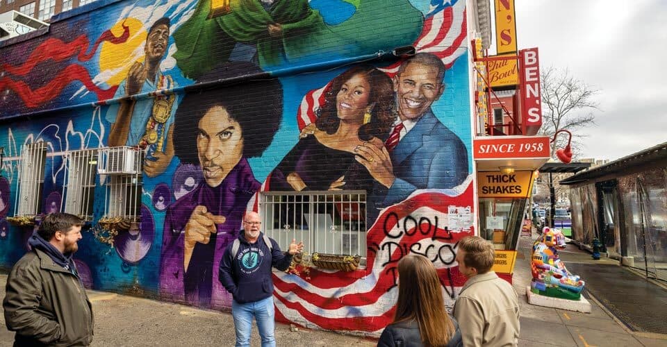 tour guide speaks to couple in front of mural