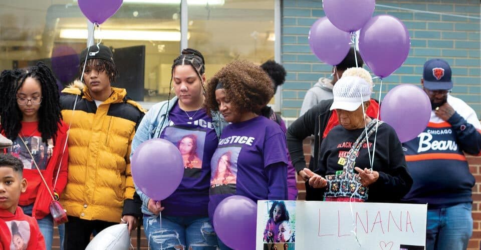 crowd gathers and mourns with purple balloons