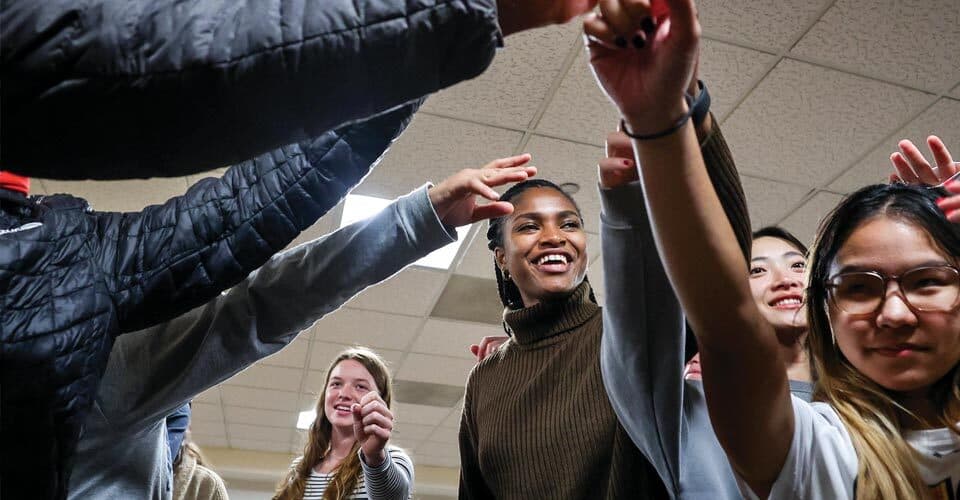 student-athletes put hands in for cheer