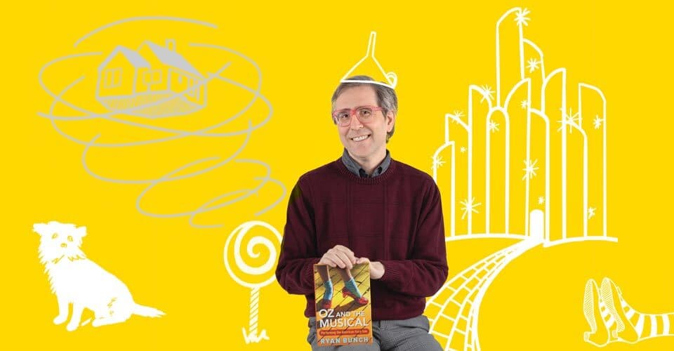 Ryan Bunch poses with "Oz and the Musical" book, on yellow background with white and gray Wizard of Oz illustrations