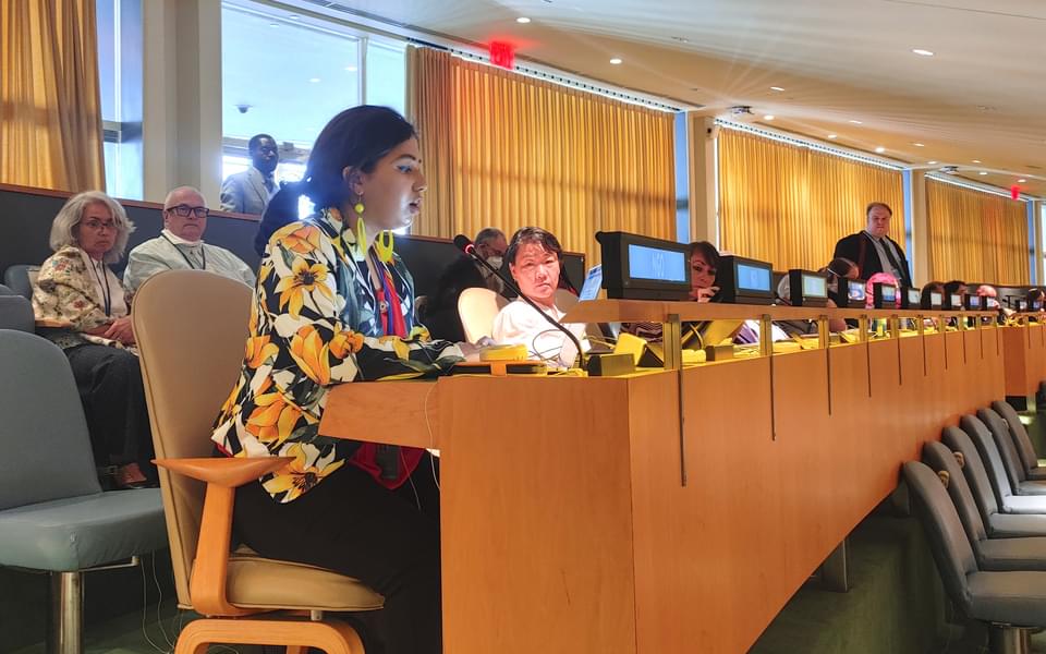 young women reads statement seated in a conference room while others look on