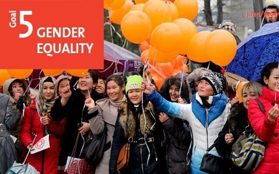 a group of women outside holding orange balloons and a sign on the top corner that reads Goal 5 Gender Equality