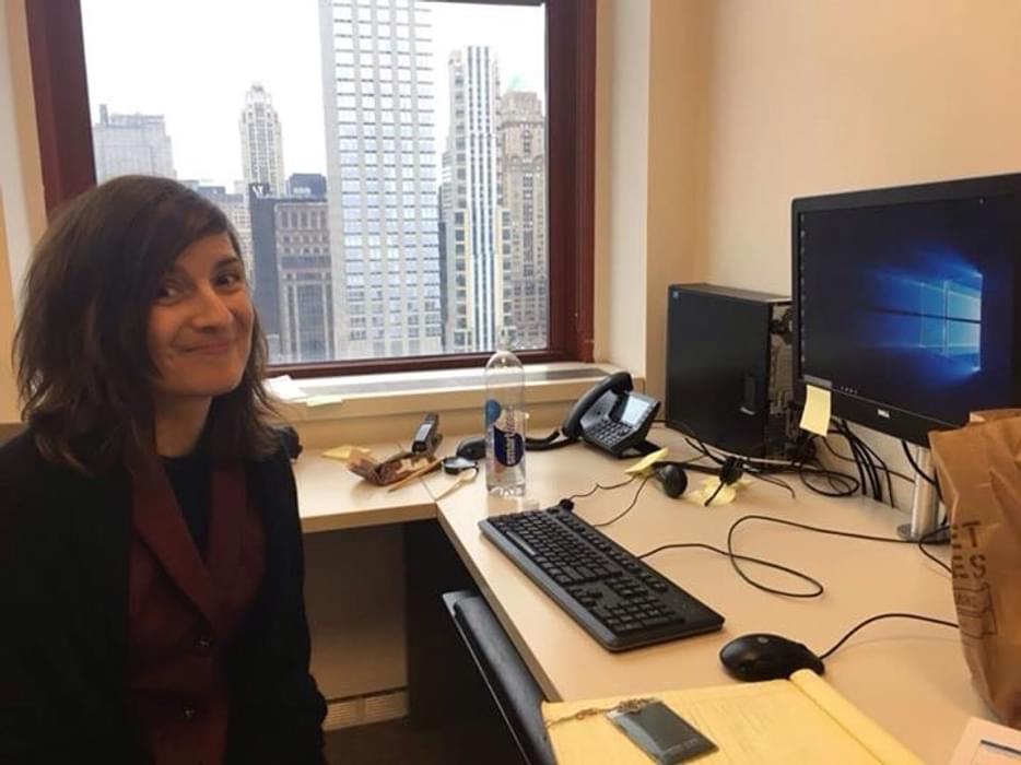 Corina sitting at her desk in front of a computer in her New York City office