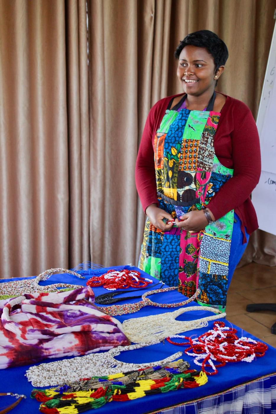 Emilie standing behind a table with handmade bags and necklaces that she sells on display