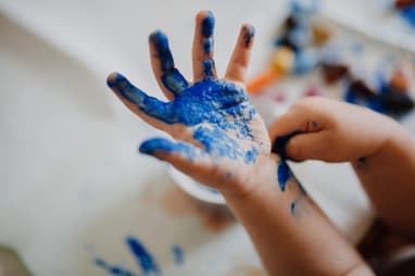 Close up of a child's hand open covered in blue paint