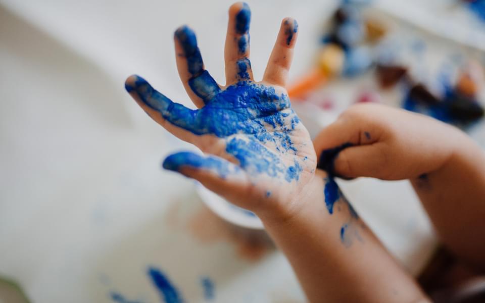 Close up of a child's hand open covered in blue paint