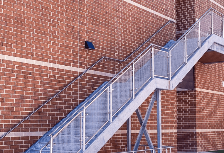 An image of concrete stairs with a mesh cable railing infill.