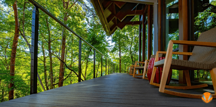 Cable railing on a wooden deck surrounded by trees.