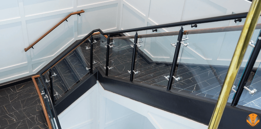 Modern staircase with glass and metal railings featuring wood accents.