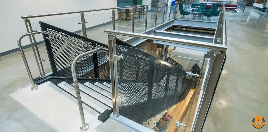Modern indoor staircase with stainless steel and glass railings designed to meet code compliance standards.