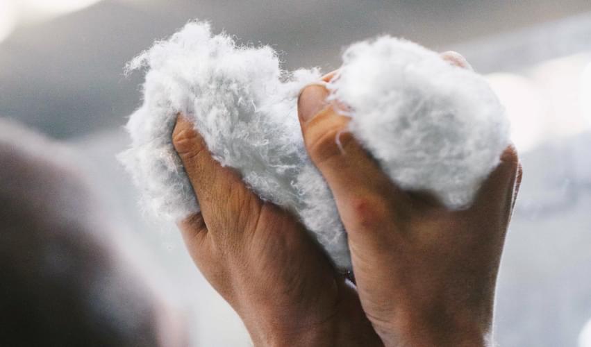 Recover™ recycled cotton fibers in white, made from post-industrial and post-consumer origins, manipulated by a Recover employee. Ready to be packed and sent to one of our strategic partners in the textiles industry.