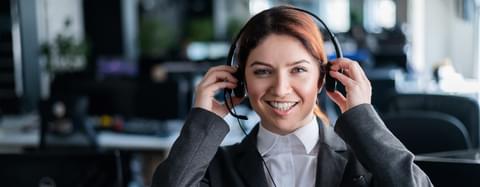Happywomanwithheadphonesinhandsworkinginacallcenter