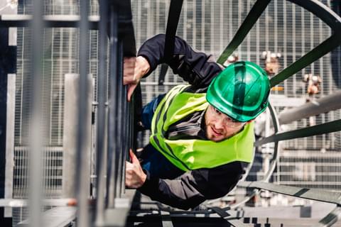 Man climbing ladder in hi vis