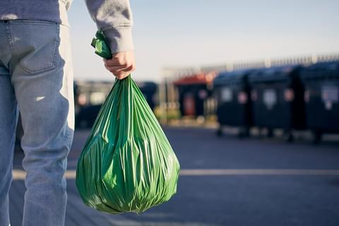 Man walking with rubbish hand carrying plastic LR