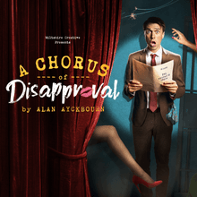 A Chorus of Disapproval by Alan Ayckbourn. A man is standing by a curtain holding a script looking scared. A hand is reaching towards the man’s head and a stockinged leg is poking out from behind the curtain.