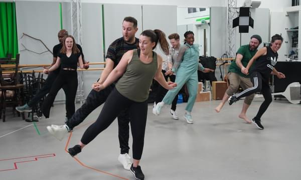 Nicola Bryan, Tom Self, Lucy Elizabeth Thorburn, Jammy Kasongo, Chioma Uma and Luke Thornton dancing during rehearsals for ‘Brief Encounter’. They are in pairs, and all have their right leg raised to the side whilst their left remains on the ground. The person at the back of each pair reaches forward to hold hands of those in front.