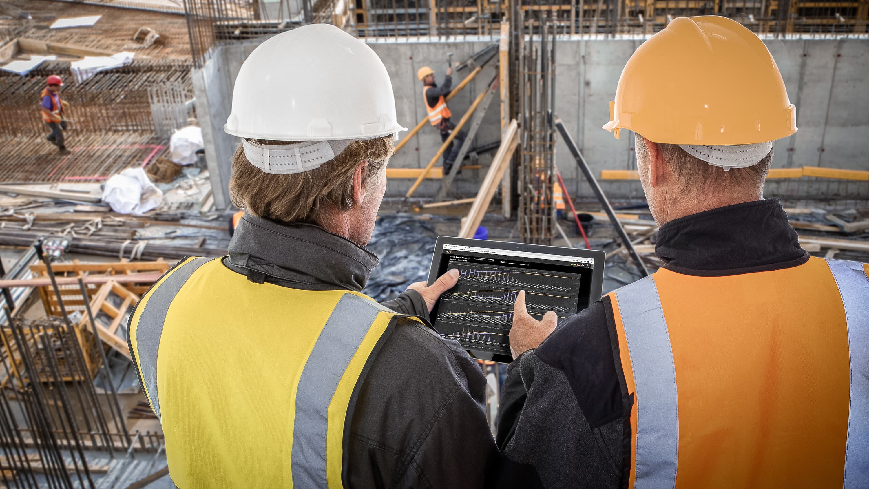 Asset owner and general contractors review XYZ Project controls dashboard on a tablet